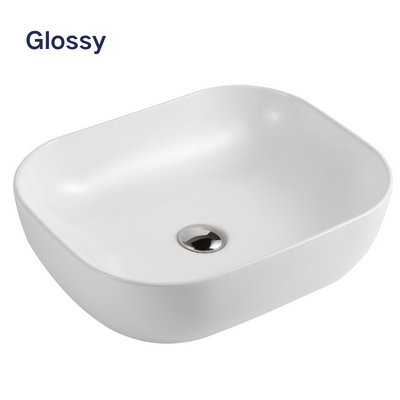 Modern white glossy ceramic vessel sink with rounded corners and chrome pop-up drain for bathroom vanity.