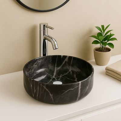 Modern black marble round vessel sink with white veining and chrome faucet on a white bathroom vanity.